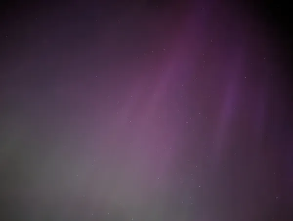 Faint green and purple Northern Light streaks in the night sky.