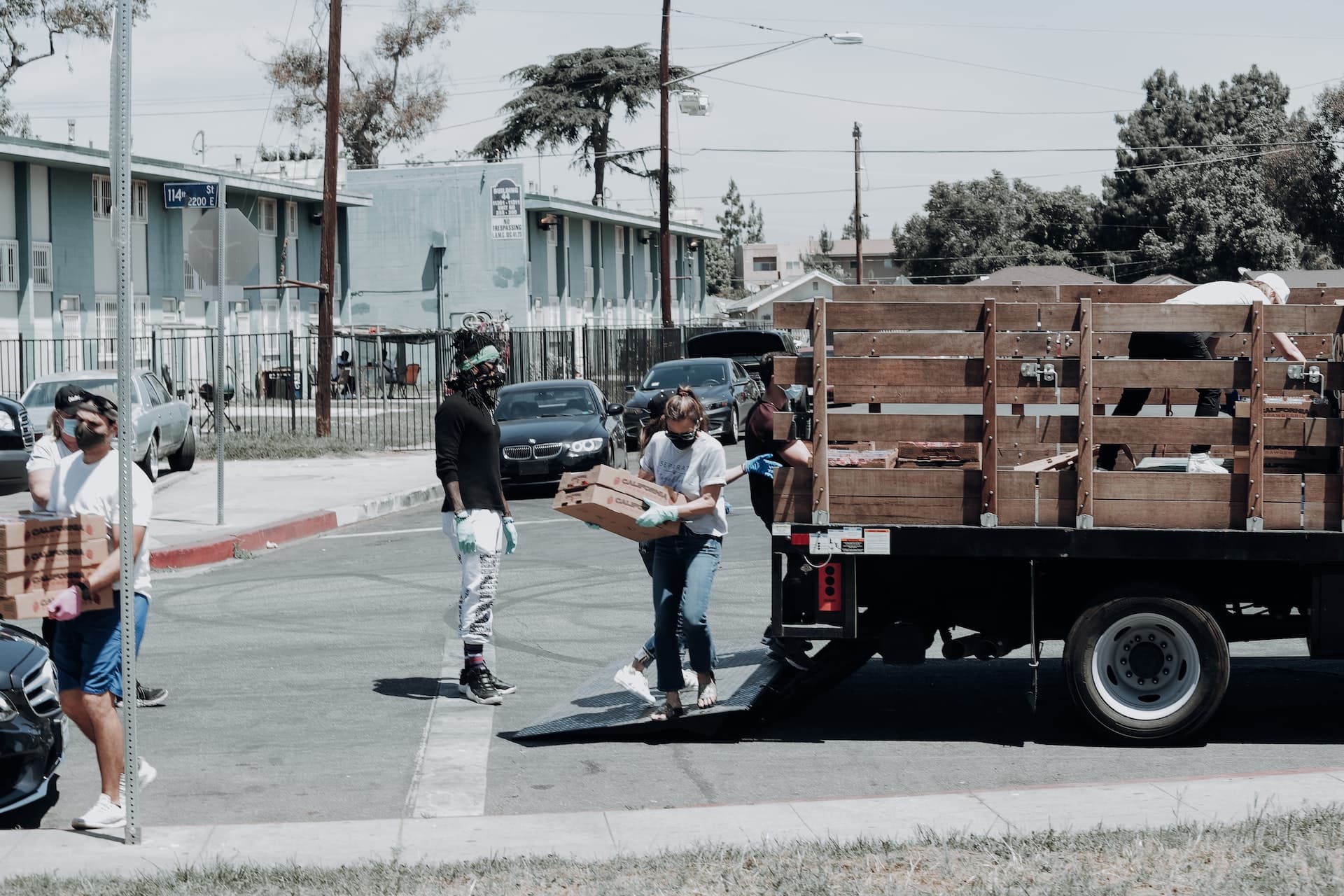 People unloading boxes of food from a truck in the street.