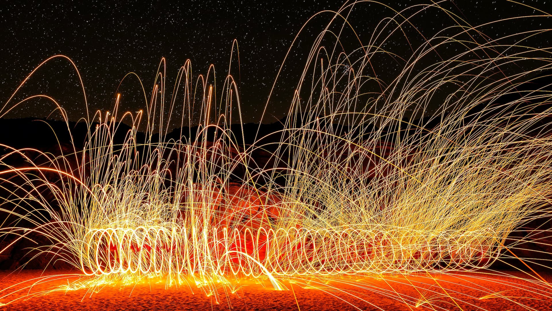 Long exposure photo of a fire poi player. It's dark, there are a lot of traces left by sparks.
