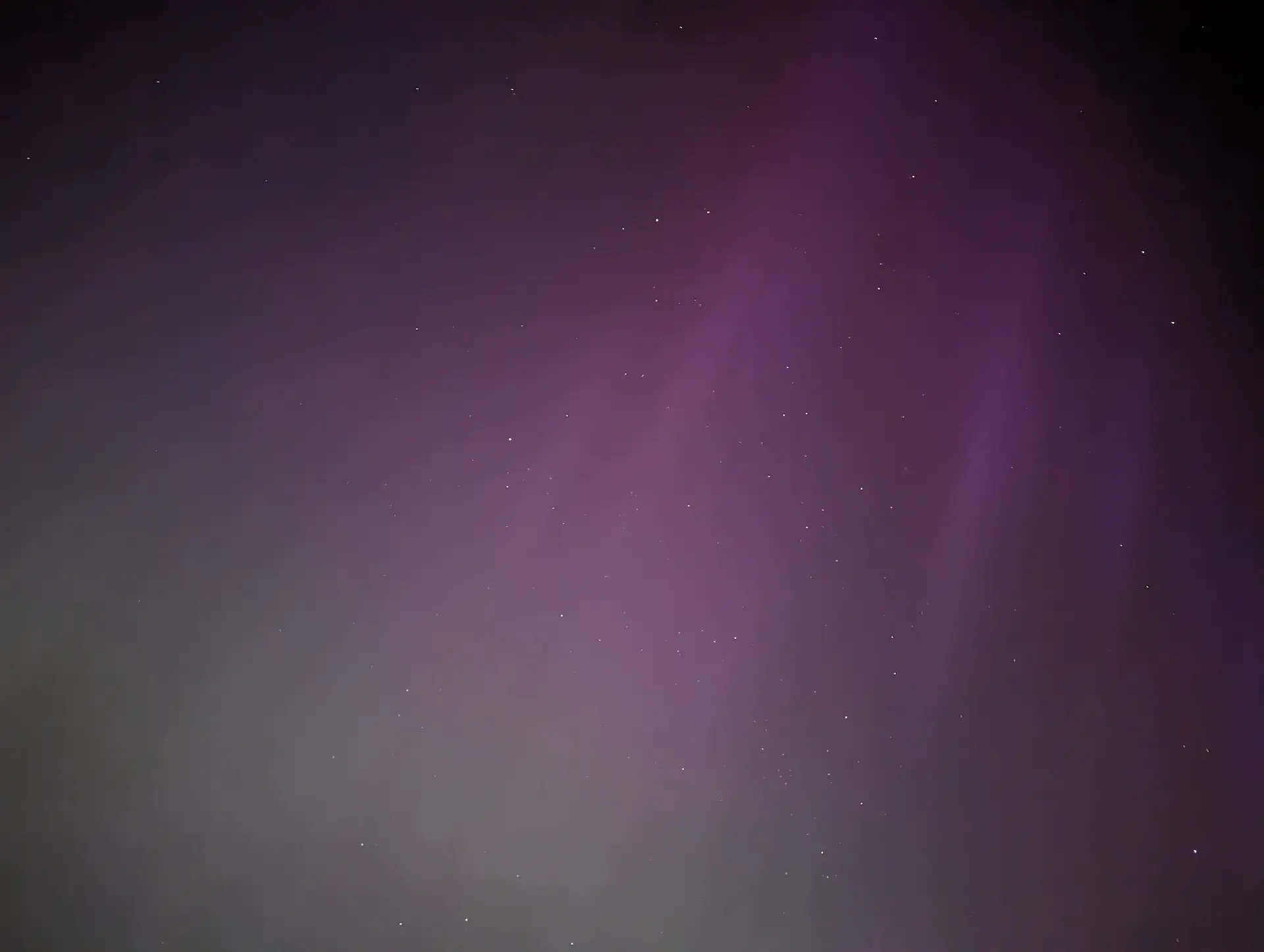 Faint green and purple Northern Light streaks in the night sky.