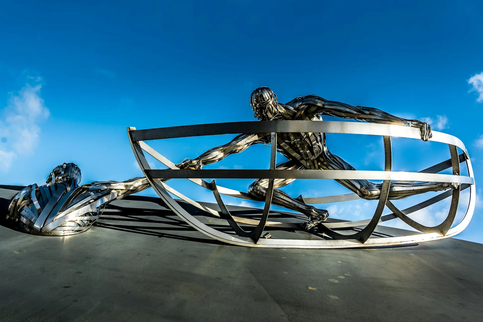 Metal sculpture of a man in a boat saving another man from water.