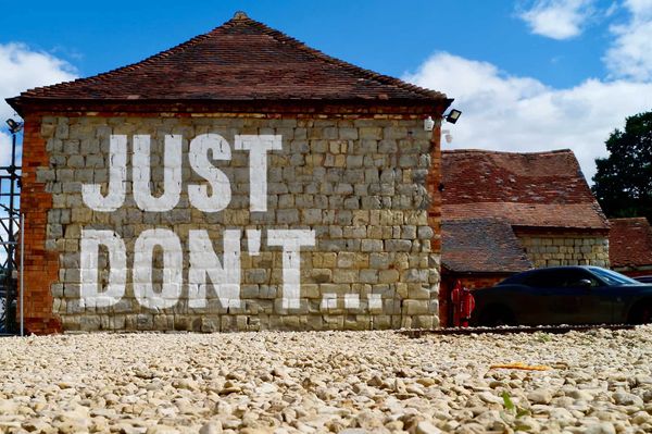 Photo of a crumbling house with the words "just don't" painted on its face with huge white letters.