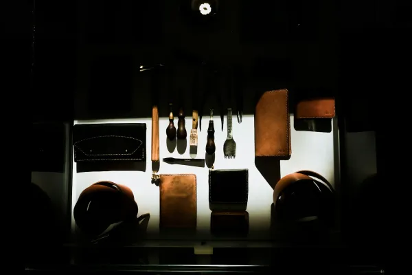 Dark image of a table from above with a spotlight illuminating leatherworking tools and materials.