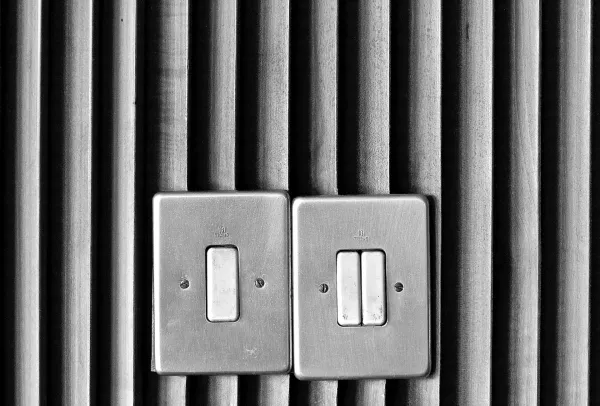 Two light switches on textured wooden wall. One is a double switch.