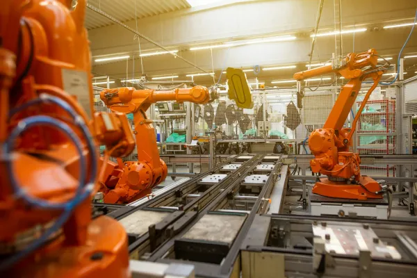 A few 6-axis orange industrial assembly robots on a production line.