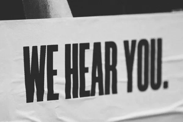 The words ”we hear you” printed on a white banner in all caps.